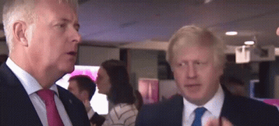 Two Men In Suits And Ties Are Standing Next To Each Other In A Room . GIF