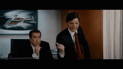 Two Men In Suits And Ties Are Standing Next To Each Other In An Office With A Helicopter In The Background . GIF