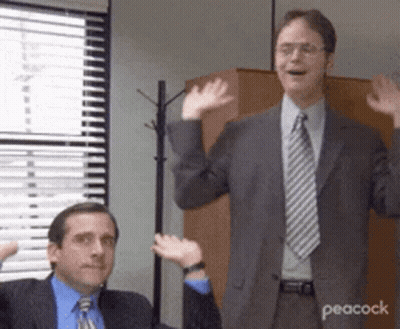 Two Men In Suits And Ties Are Waving Their Hands In A Room . GIF