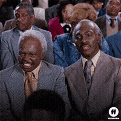 Two Men In Suits And Ties At Table With Drinks GIF