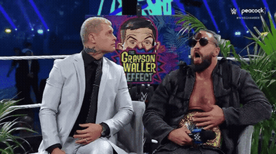 Two Men In Suits Are Sitting Next To Each Other On A Couch And Talking . GIF