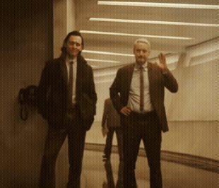 Two Men In Suits Are Standing In A Hallway GIF