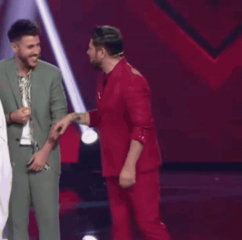Two Men In Suits Are Standing Next To Each Other And Laughing On A Stage . GIF