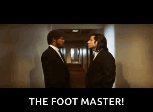 Two Men In Suits Are Standing Next To Each Other In A Hallway And One Of Them Is Saying `` The Foot Master '' . GIF