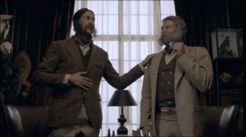 Two Men In Suits Are Standing Next To Each Other In A Room GIF