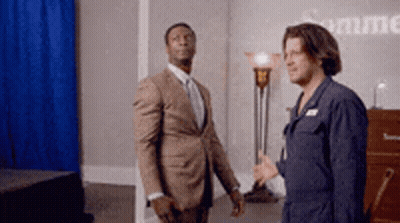 Two Men In Suits Are Standing Next To Each Other In A Room With A Blue Curtain Behind Them . GIF