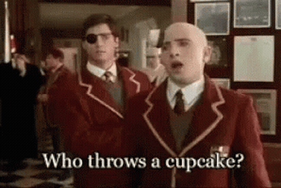 Two Men In Suits Asking Who Throws A Cupcake GIF