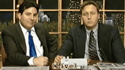 Two Men In Suits At Table With Live Sign GIF