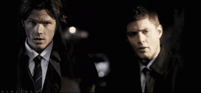 Two Men In Suits Holding Badge In Dark Room GIF