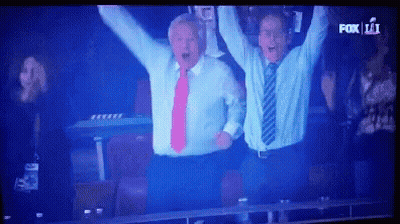 Two Men In Suits Raising Arms In Front Of Fox 11 Screen GIF