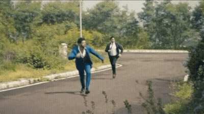 Two Men In Suits Running Down Road In Woods GIF