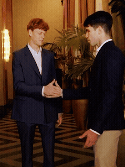 Two Men In Suits Shake Hands Near Plant GIF