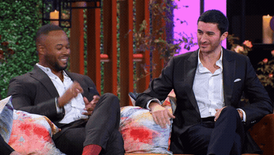 Two Men In Suits Sitting On Couch Talking GIF