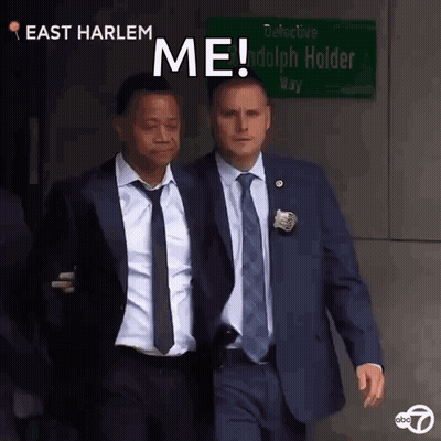 Two Men In Suits Walking Past East Harlem Sign GIF
