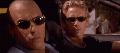 Two Men In Sunglasses Looking At Each Other In Car GIF