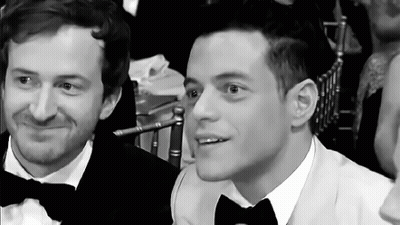 Two Men In Tuxedos And Bow Ties Are Sitting Next To Each Other At A Table . GIF