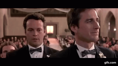 Two Men In Tuxedos And Bow Ties Are Standing Next To Each Other In A Church . GIF