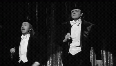 Two Men In Tuxedos And Top Hats On Stage GIF