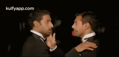 Two Men In Tuxedos Are Hugging Each Other . GIF