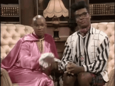 Two Men In Tuxedos Sitting In Director Chairs Talking GIF