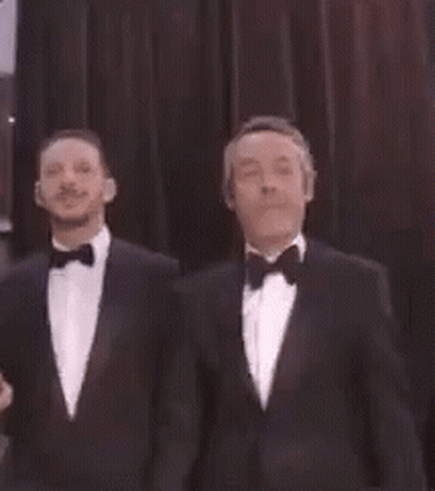 Two Men In Tuxedos Standing GIF