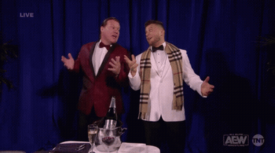 Two Men in Tuxedos With Blue Curtain Saying Live