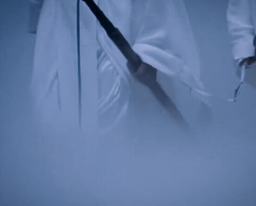 Two Men In White Robes Are Holding Swords And Walking In A Cave GIF