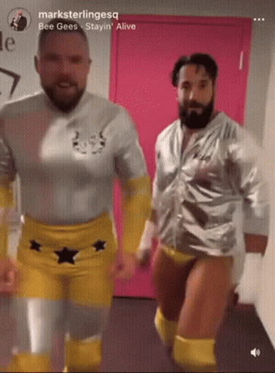 Two Men In Wrestling Outfits Are Dancing In Front Of A Pink Door With The Words " Bee Gees Stayin Alive " On The Bottom GIF
