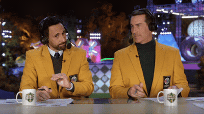 Two Men in Yellow Jackets and Headphones at Table With Golf Channel Cup