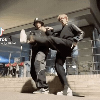 Two Men Kicking Each Other In Front Of Tik Tok Building GIF