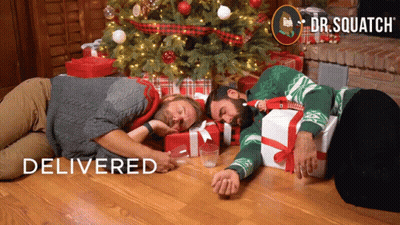 Two Men Laying In Front Of Christmas Tree Dr. Squatch GIF