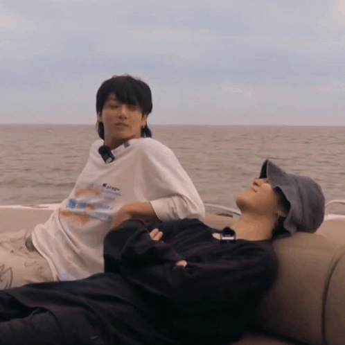Two Men Laying On A Boat With One Wearing A Shirt That Says ' Abercrombie & Fitch ' GIF
