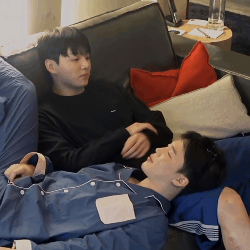 Two Men Laying On A Couch With One Wearing A Shirt That Says ' Abercrombie & Fitch ' GIF