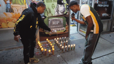 Two Men Lighting Candles At RIP Sign GIF