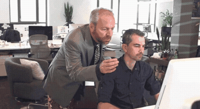 Two Men Looking At Computer Screen One Holding Cup GIF