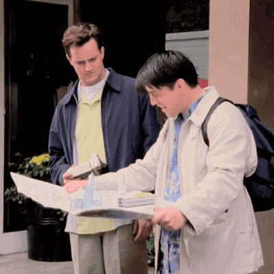 Two Men Looking At Map One With Backpack GIF