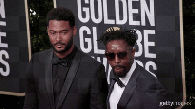Two Men On A Red Carpet With A Sign That Says Golden Globe On It GIF