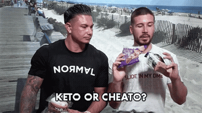 Two Men On Boardwalk One With Keto Or Cheato Shirt GIF