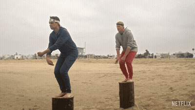 Two Men On Logs At Beach With Netflix GIF