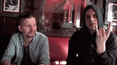 Two Men On Red Couch In Front Of The Museums Sign GIF