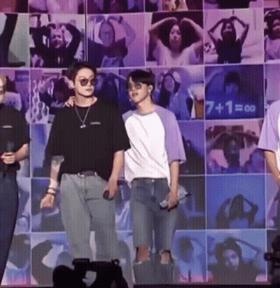 Two Men On Stage In Front Of Picture Wall GIF
