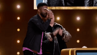 Two Men On Stage With Arms Outstretched One Wearing Glasses GIF