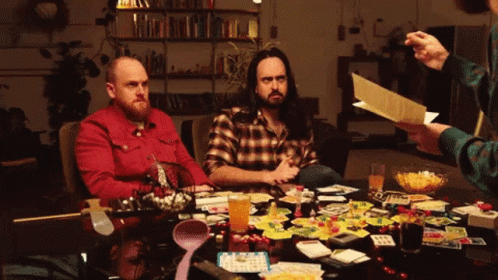 Two Men Playing Board Game While Man Holds Paper GIF