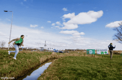 Two Men Playing Frisbee In Field With Recycling Sign GIF