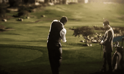 Two Men Playing Golf On A Lush Green Course GIF