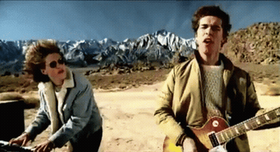 Two Men Playing Guitar And Keyboard In Desert GIF