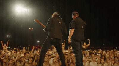 Two Men Playing Guitars In Front Of Crowd GIF