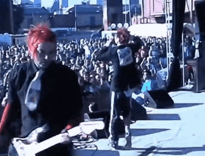 Two Men Playing Guitars On Stage GIF