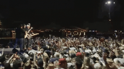 Two Men Playing Guitars On Stage GIF