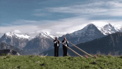 Two Men Playing Horns In Front Of Mountain Range GIF